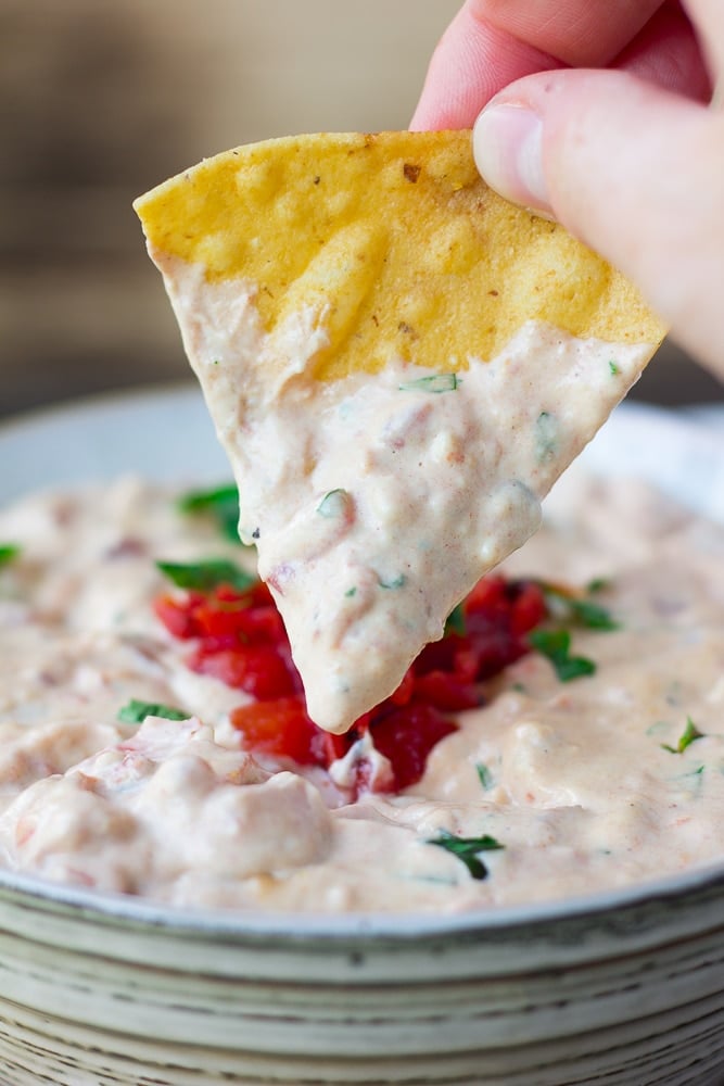 vegan queso in a bowl with chip being dipped into it