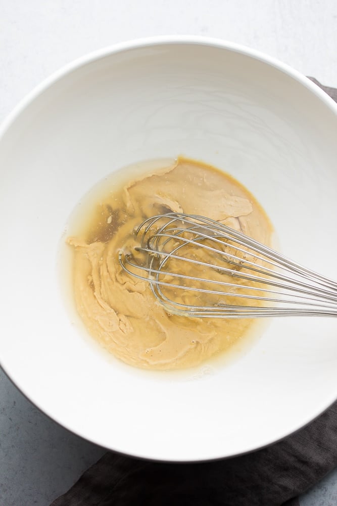 showing how to make dressing in a white bowl with whisk