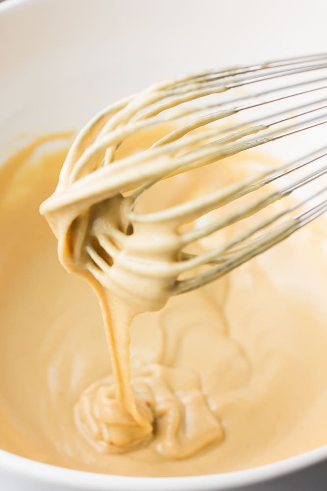 whisk in bowl of lemon tahini dressing