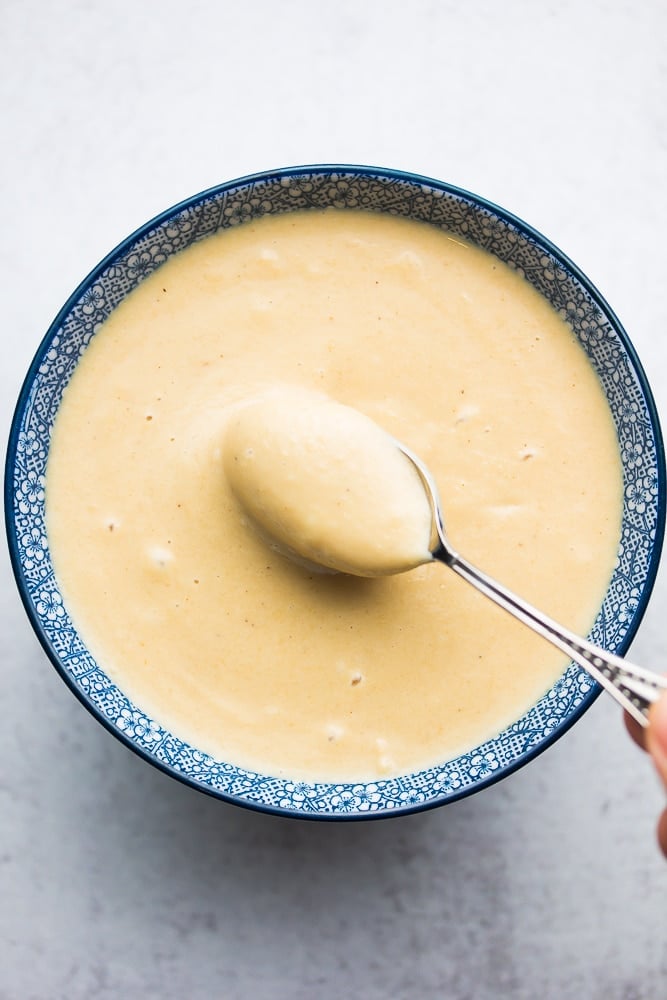 silver spoon in bowl of creamy lemon tahini dressing