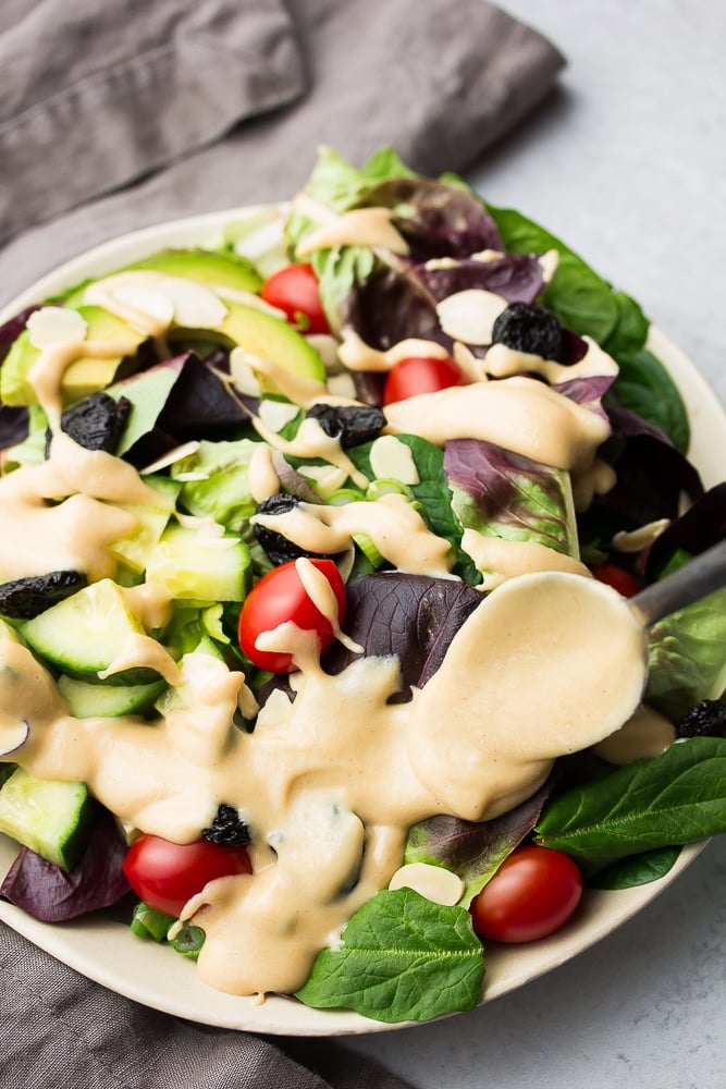 close up of creamy dressing being spooned onto salad
