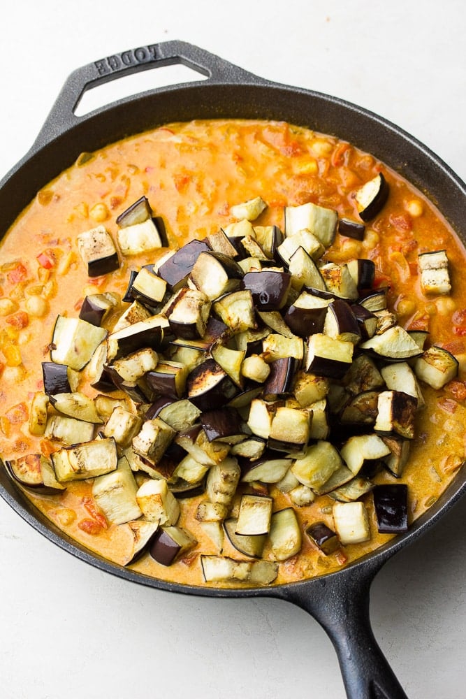 curry mixture with roasted eggplant being added to the top