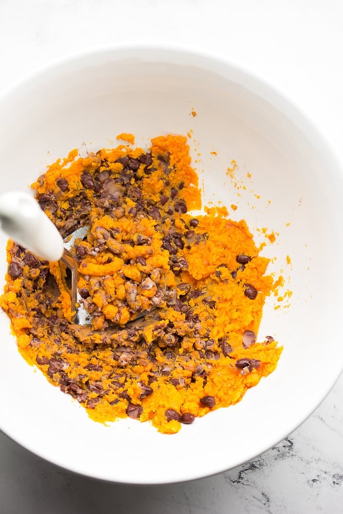 bowl mashing cooked sweet potato with black beans