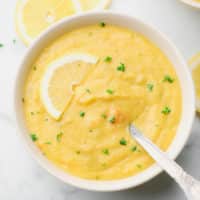 square image of a bowl of yellow soup with a spoon in it