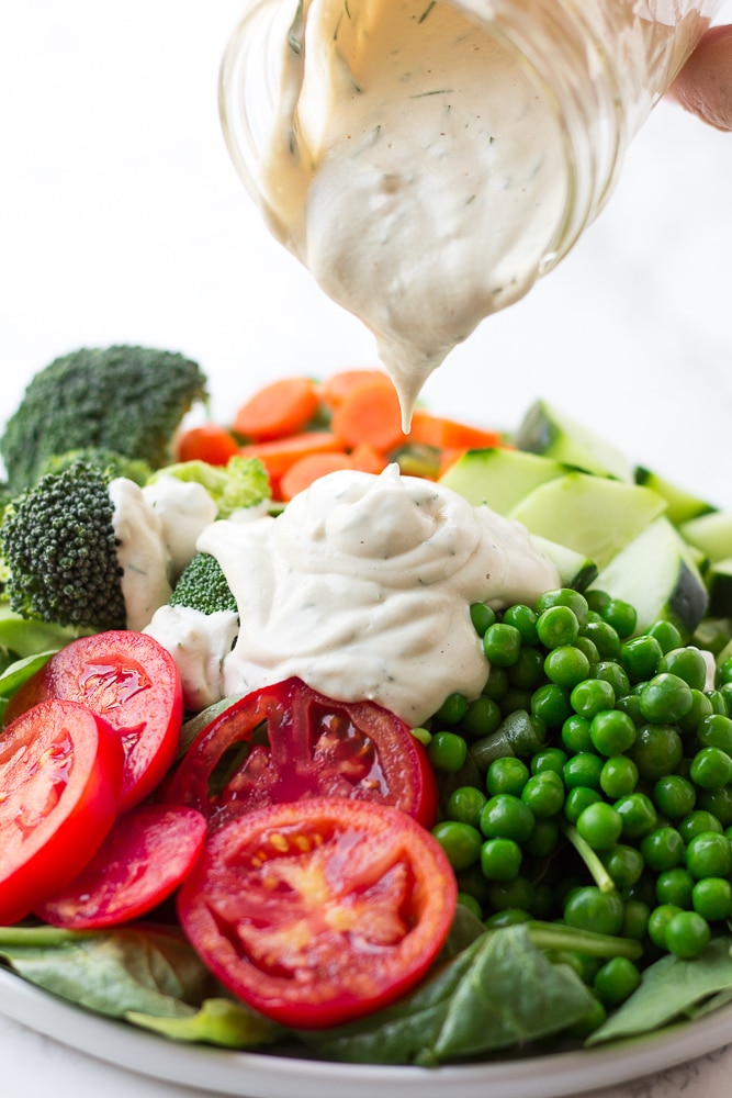 vegan ranch being poured onto a large salad