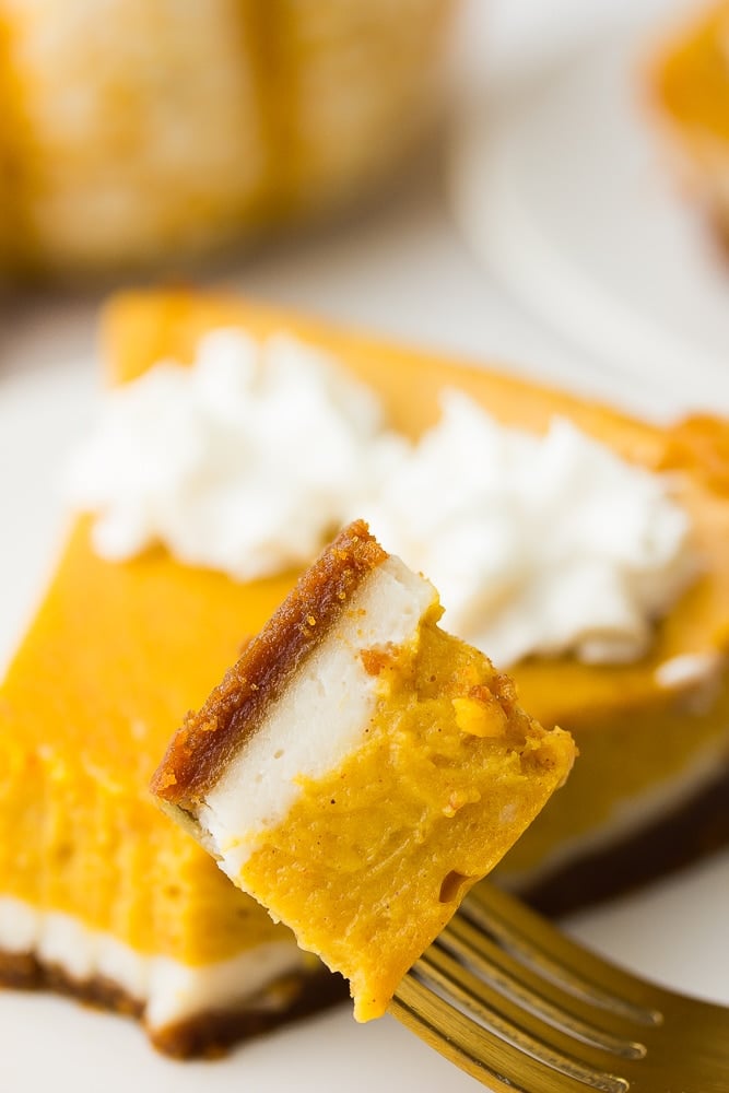 a bite taken of vegan double layered pumpkin cheesecake on a fork