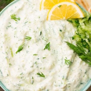 bowl of vegan tzatziki with lemon slices and dill