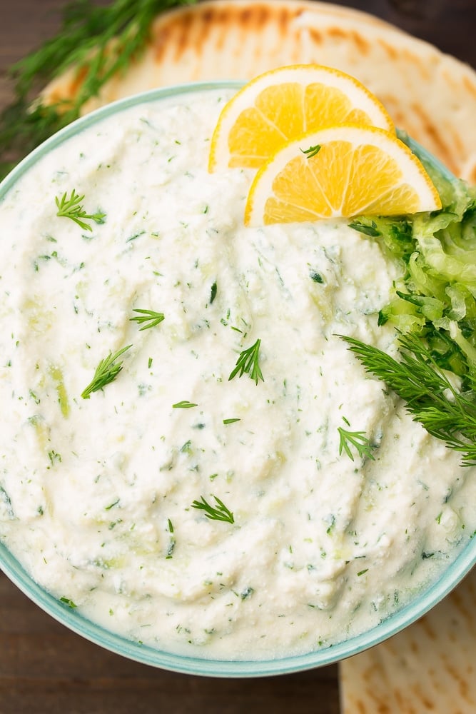 bowl of vegan tzatziki with lemon slices and dill