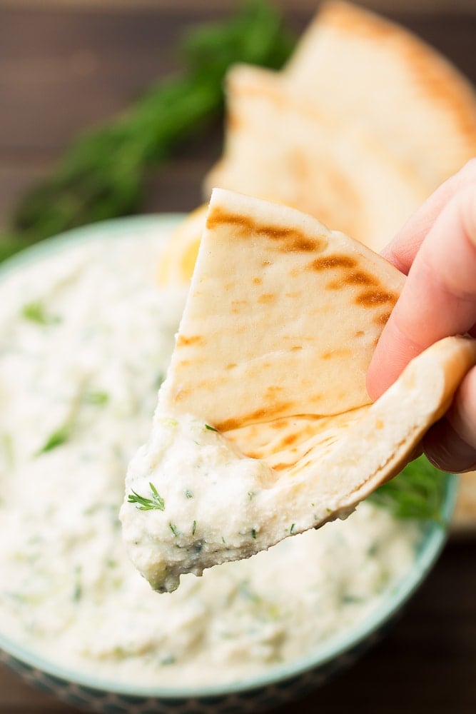 pita bread being dipped into tzatziki