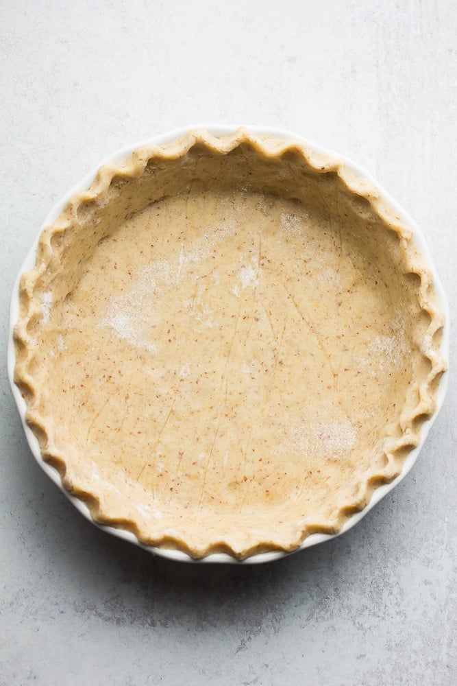 an uncooked healthy pie crust with grey background, nicely in pie pan