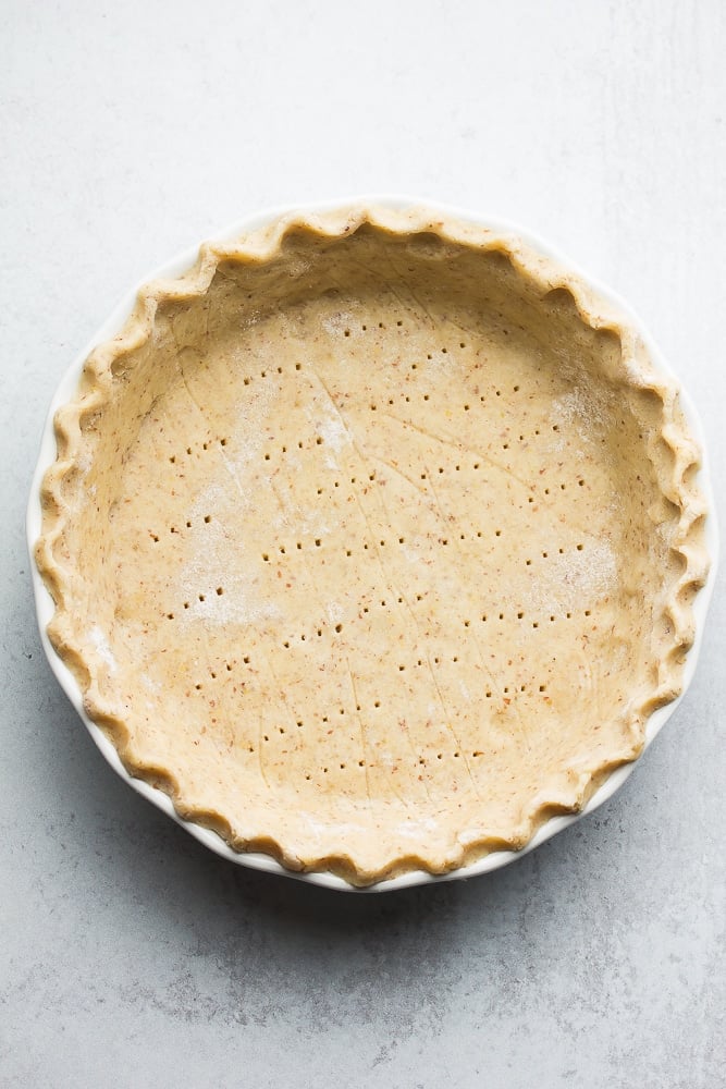 uncooked pie crust with fork holes in it, grey background