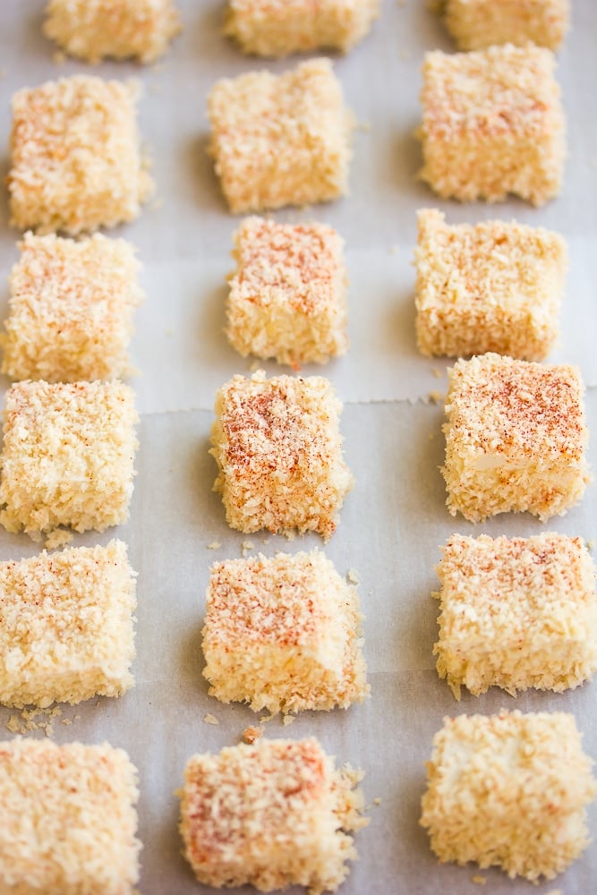 uncooked breaded nuggets on a pan with parchment paper.