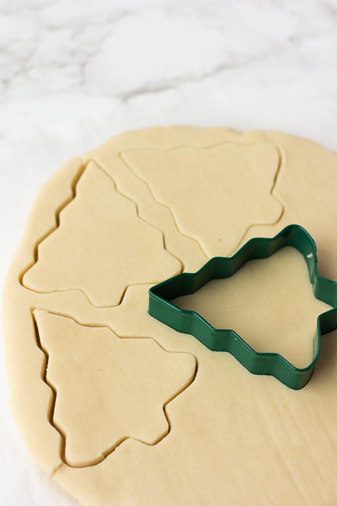 vegan sugar cookies dough being cut with christmas tree cutter