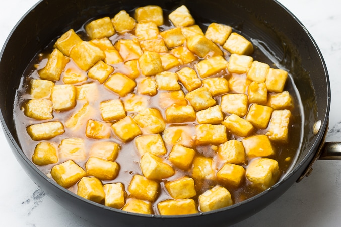 crispy tofu in orange sauce in a pan