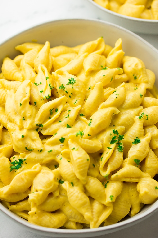 close up photo of bowl of cheesy shells with parsley