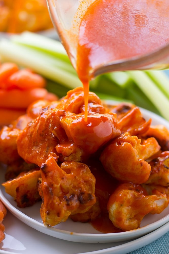 Buffalo Cauliflower Wings on a plate with sauce being poured