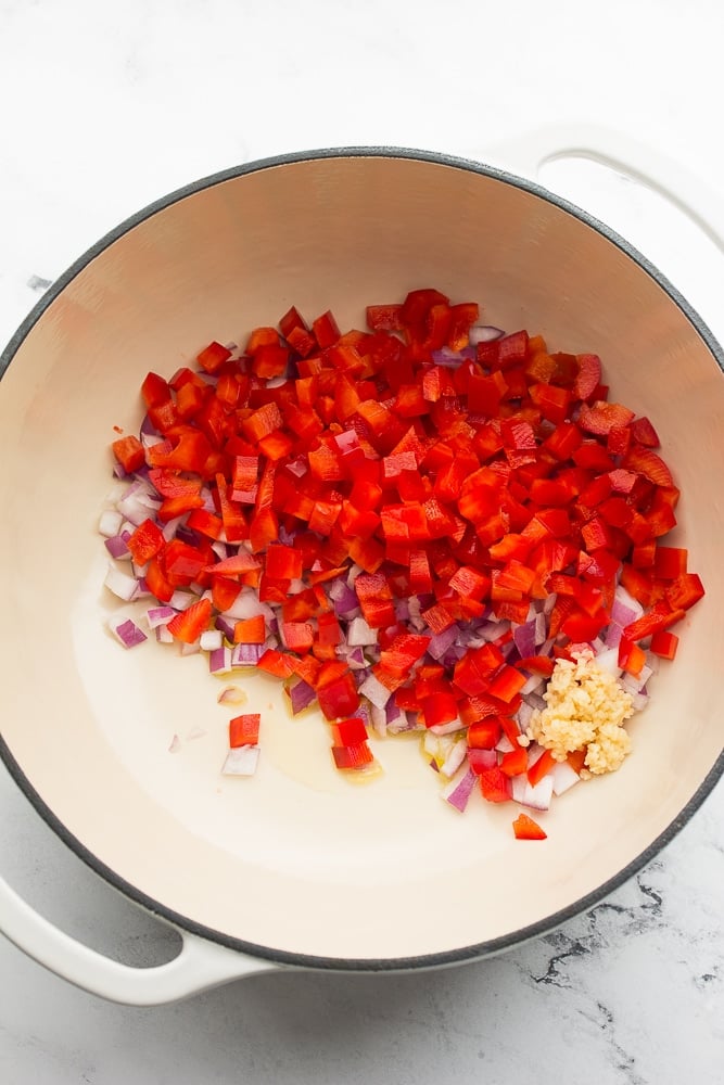 white pot with onion, red pepper and garlic