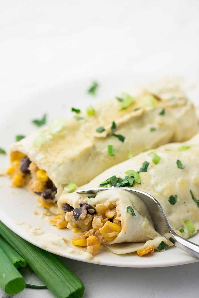 fork cutting into white enchiladas on a plate, showing inside