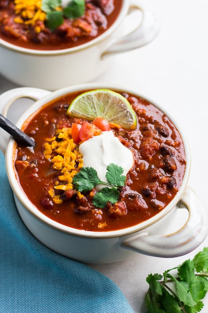 bowl of vegan chili with toppings and blue towel