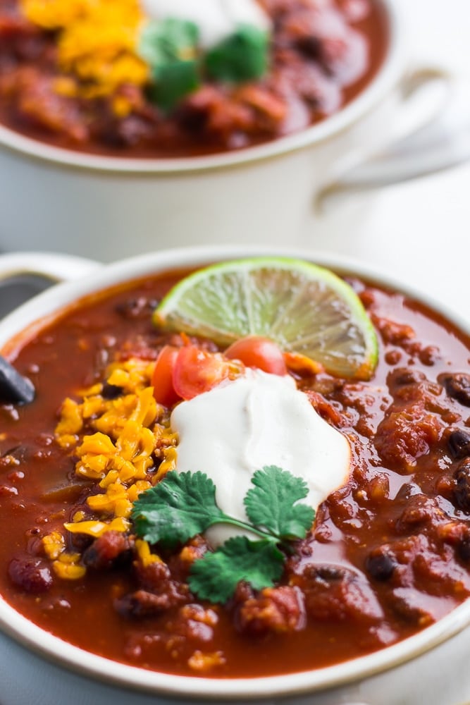 very close up of chili in a bowl with toppings such as sour cream and cheese