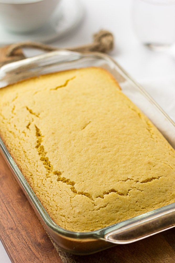 vegan cornbread in a glass pan on a wood cutting board