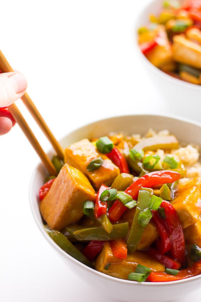 kung pao tofu on top of rice in bowl with chopsticks