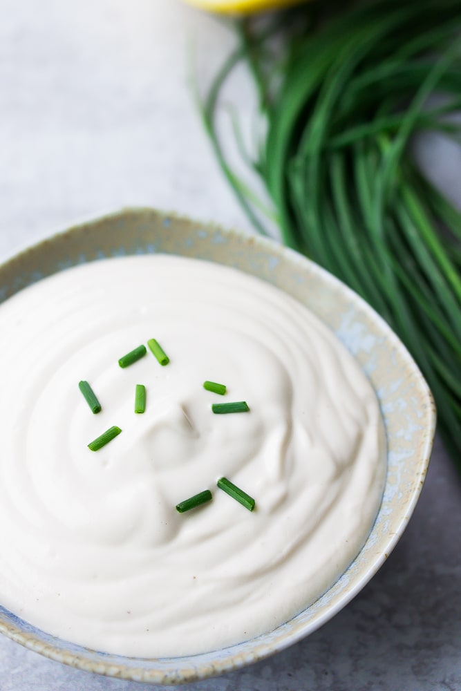 small bowl with vegan sour cream, chives sprinkled on top
