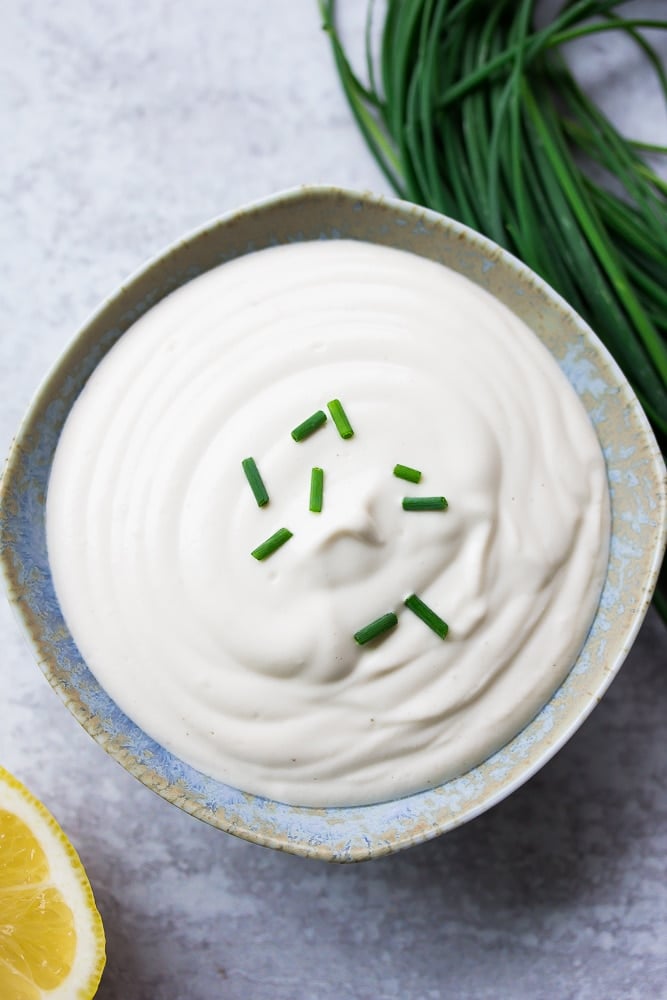 small blue bowl with vegan sour cream, chives on top