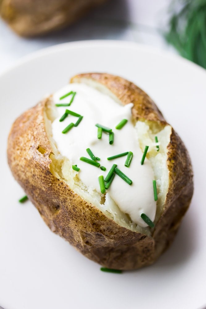 close up of vegan baked potato with vegan sour cream and chives