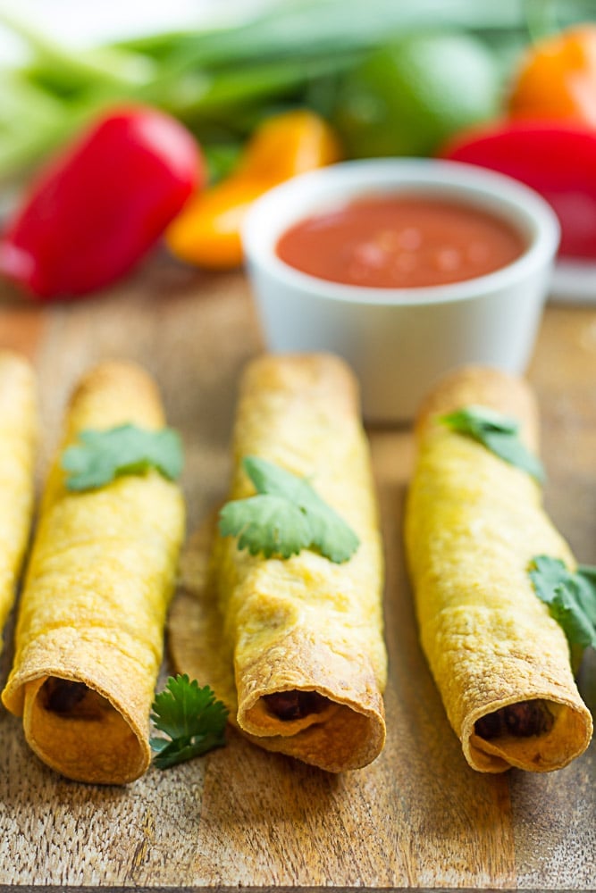 3 taquitos lined up with salsa in the background