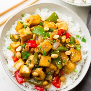 plate with white rice and kung pao tofu and peppers with peanuts on top