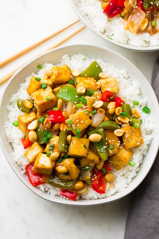 plate with white rice and kung pao tofu and peppers with peanuts on top