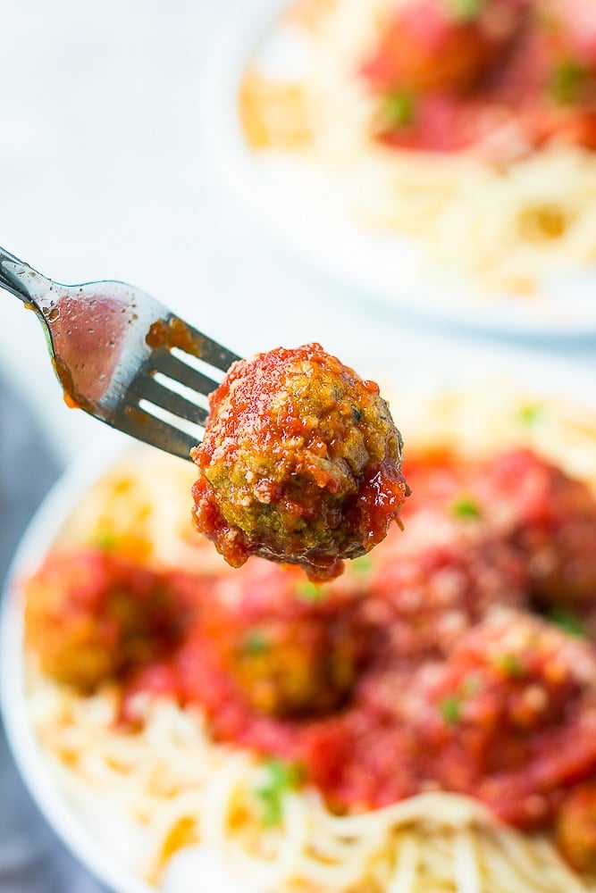 fork holding a meatball drenched in marinara