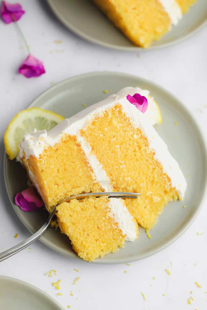 close up of a piece of vegan lemon cake with pink flowers
