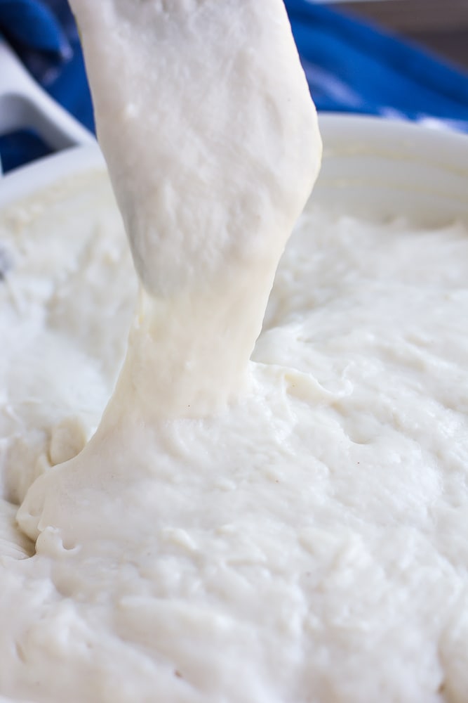 a spatula pulling up on vegan mozzarella to show how stretchy it is.