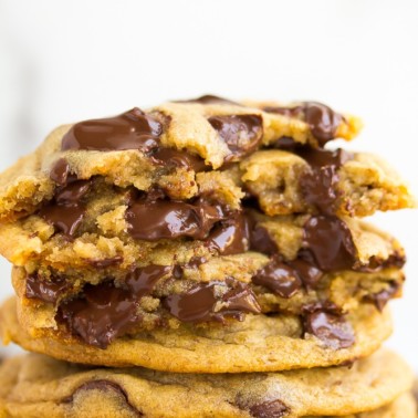 stack of chocolate chip cookies, a few broken in half showing melted chocolate.