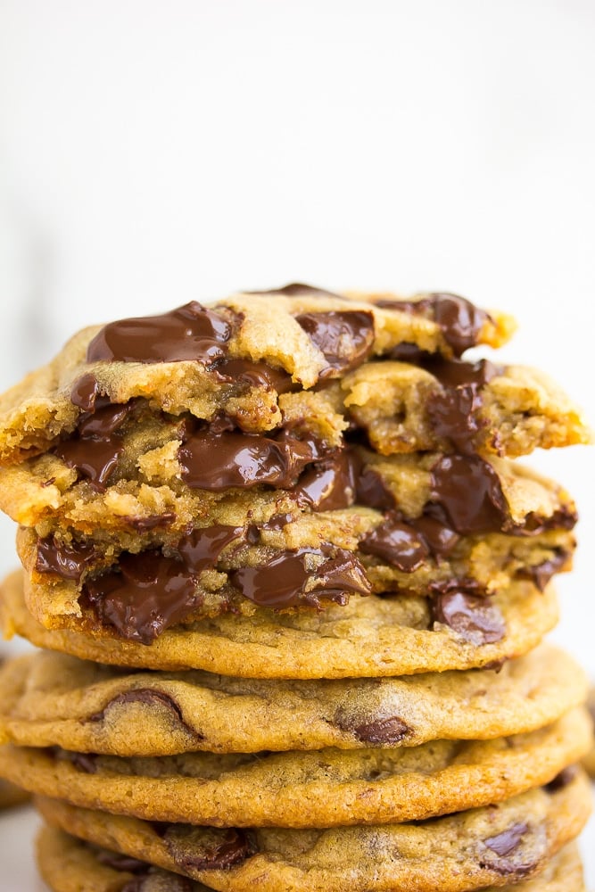 stack of chocolate chip cookies, a few broken in half showing melted chocolate.