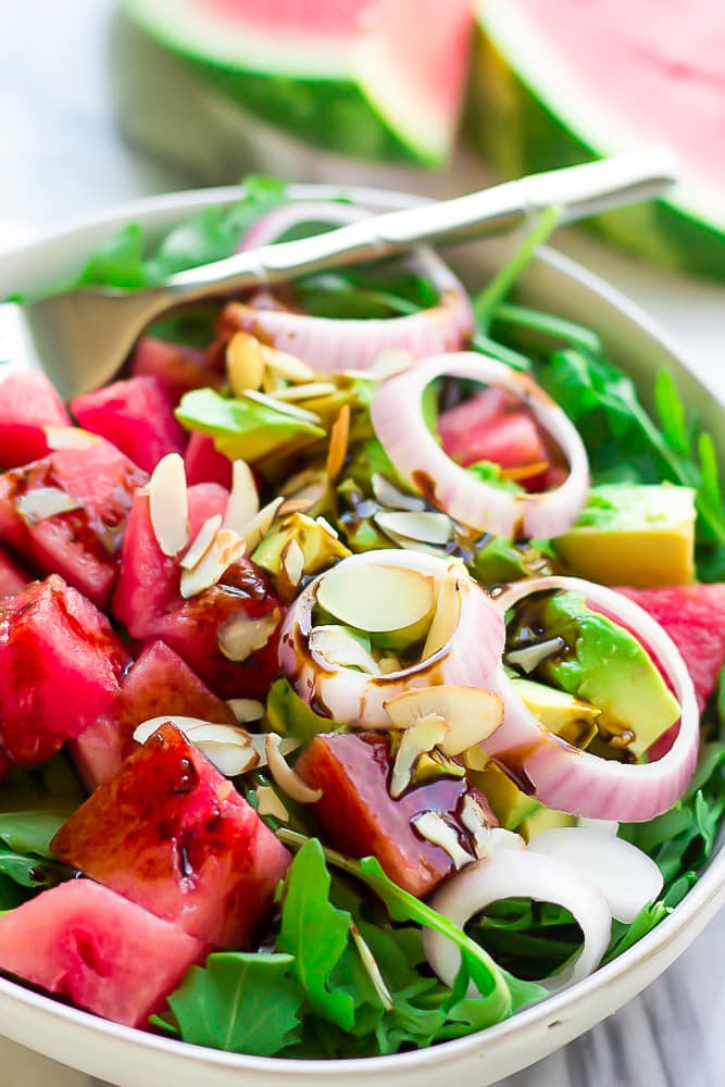 arugula watermelon salad with onions and avocado in a bowl