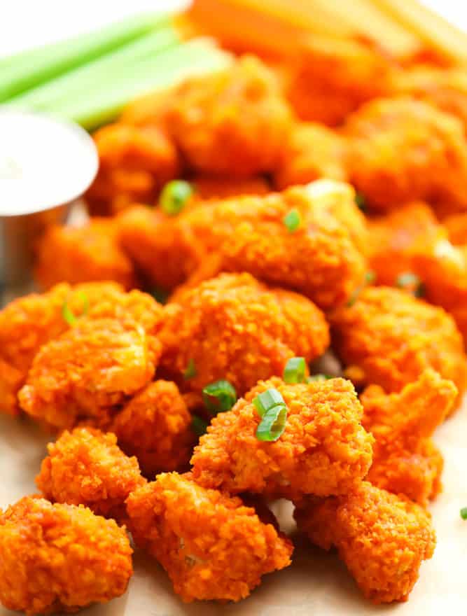 close up of crispy baked cauliflower with buffalo sauce, celery and carrots