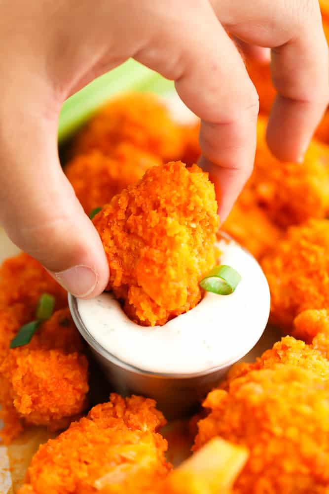 showing a hand with cauliflower piece dipped in ranch sauce