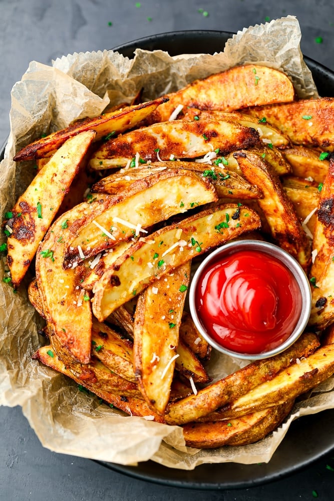 looking down on a bowl of potatoes in wedges with ketchup