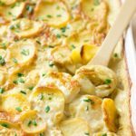 vegan scalloped potatoes in casserole dish with a wooden spoon