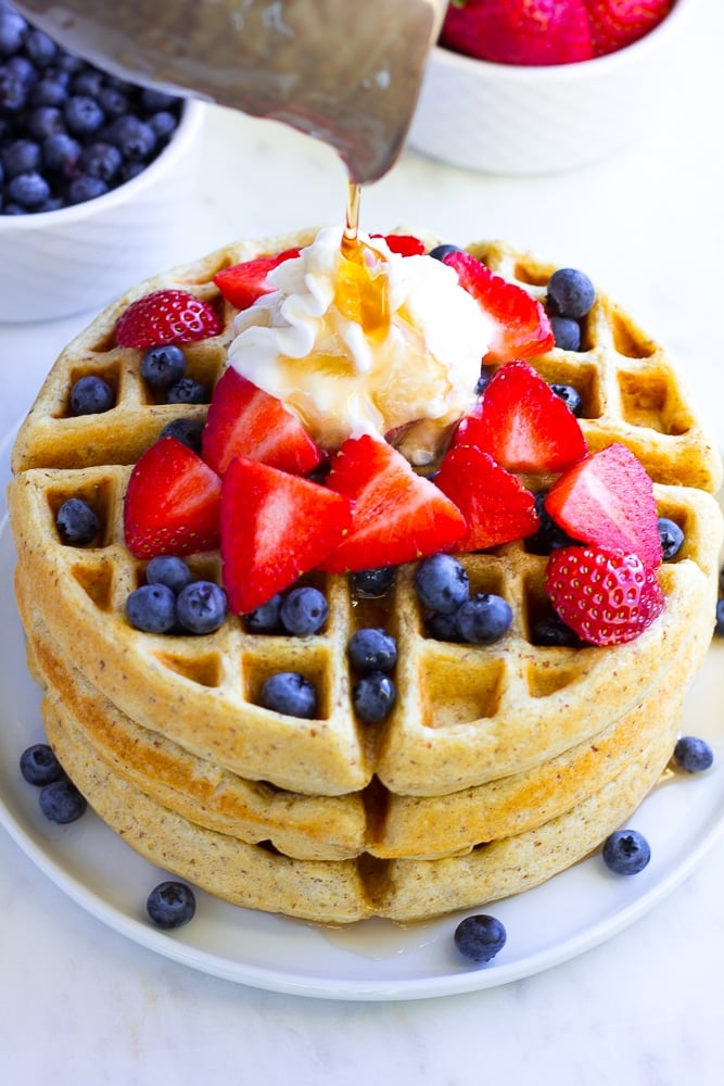 vegan waffles stacked with berries, whip and syrup.