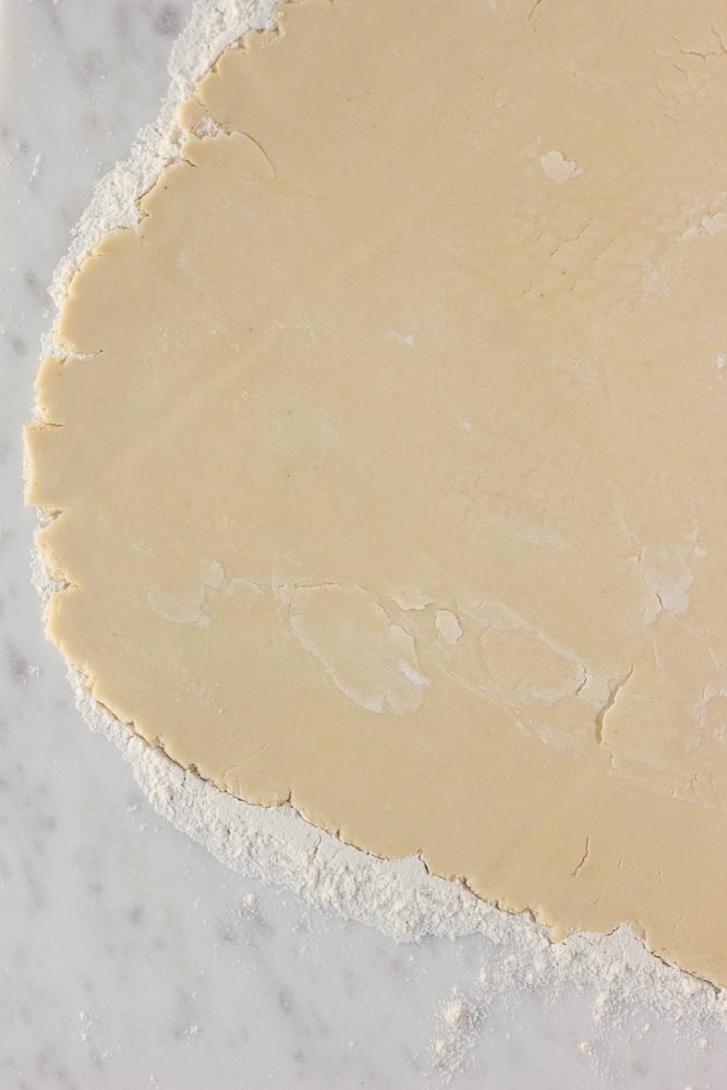 vegan pie crust being rolled on a white surface
