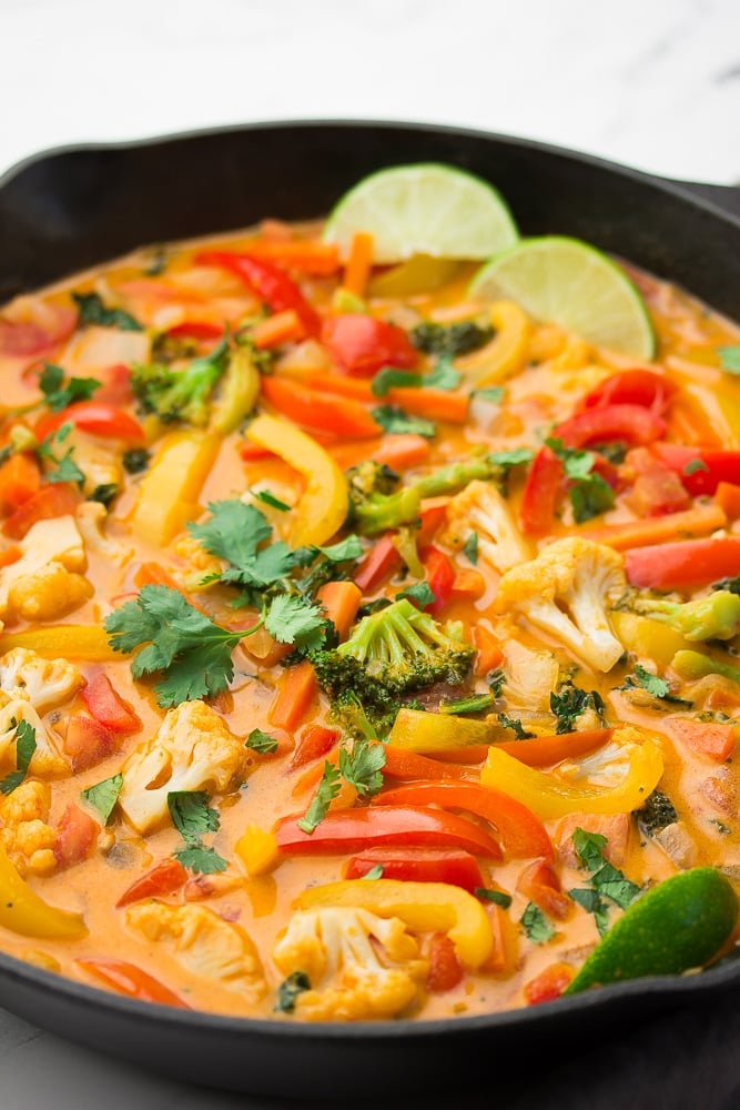 a cast iron pan full of vegetables in creamy red curry sauce