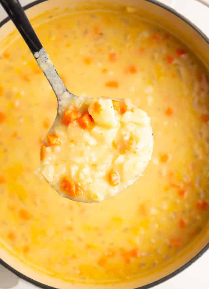 ladle holding vegan potato soup from a pot