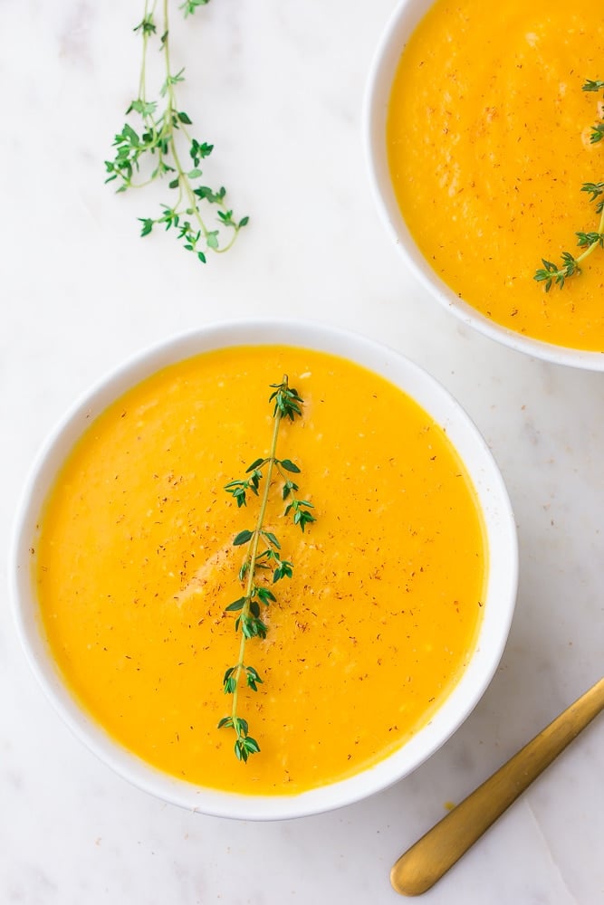 2 bowls of instant pot butternut squash soup with thyme, white background