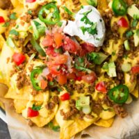 square image of vegan nachos on a plate with parchment paper