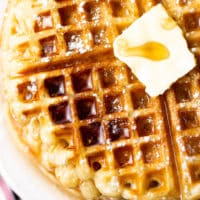 close up square image of a waffle with butter