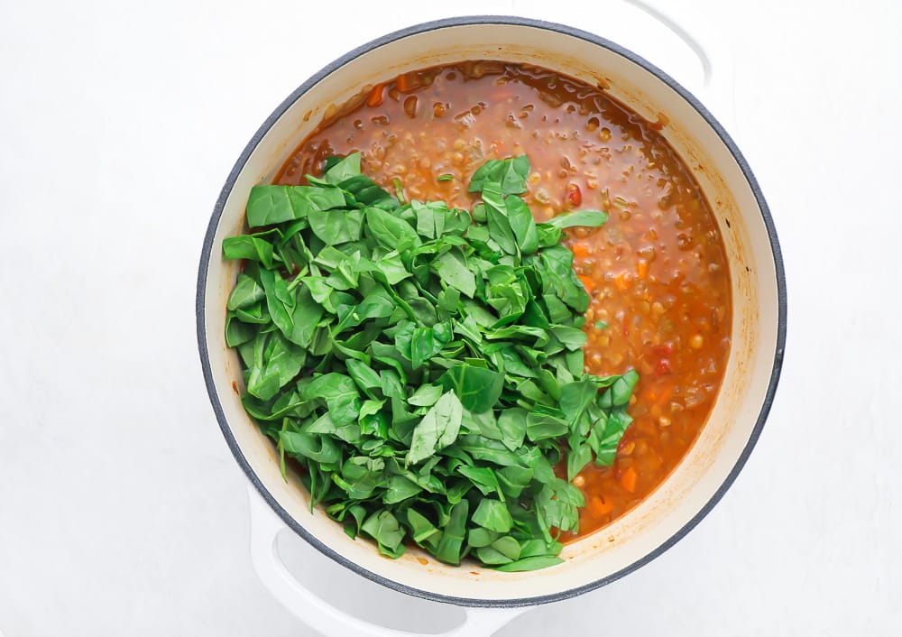 spinach being added to lentil soup